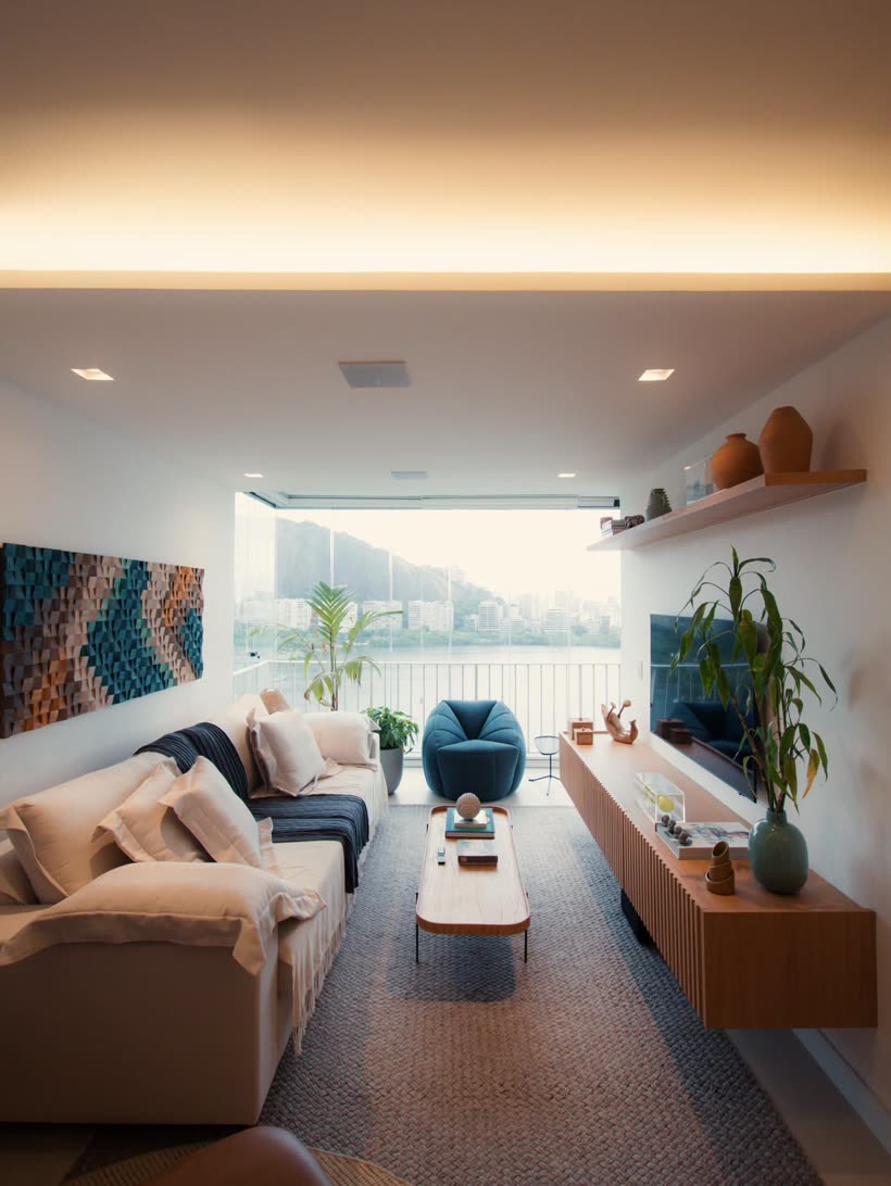 Sala de estar com vista para a Lagoa, poltrona azul e painel de madeira ripada